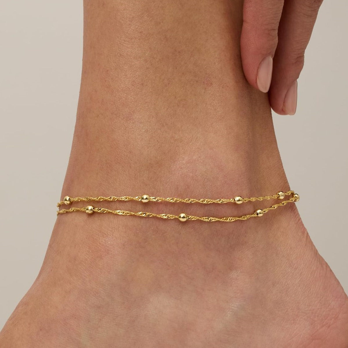 Elena double bead anklet in gold, two twisted chains with small polished beads worn on the ankle