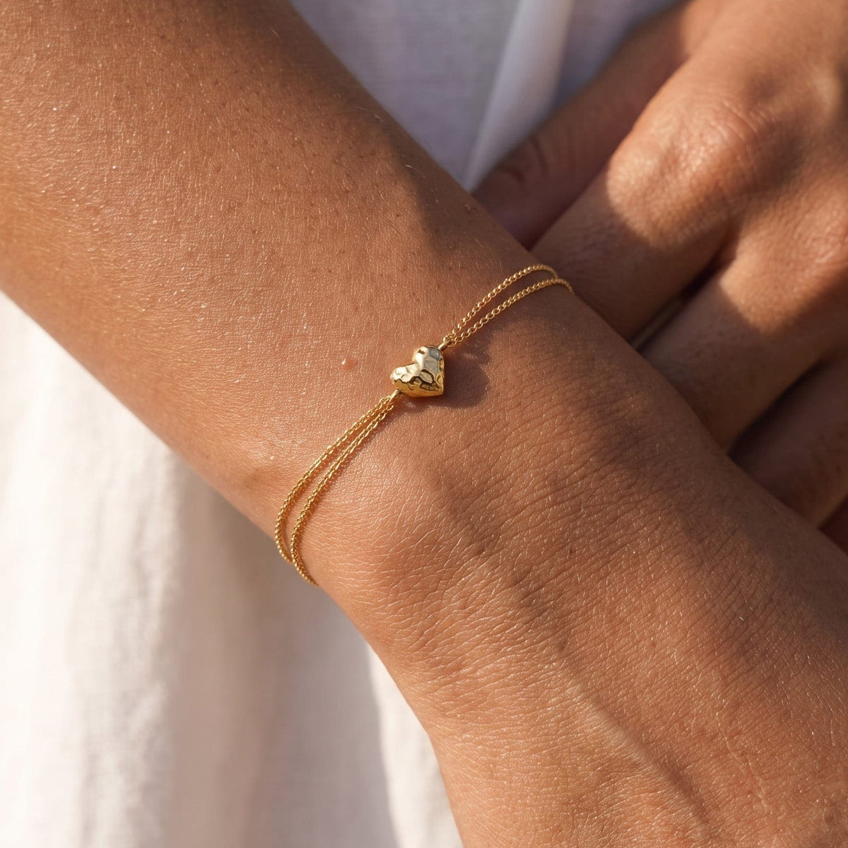 Woman wearing the Adèle hammered heart gold bracelet on the wrist