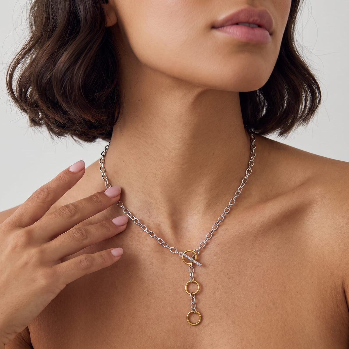 Woman wearing the Albane circle toggle two-tone necklace at the collarbone touching her neck