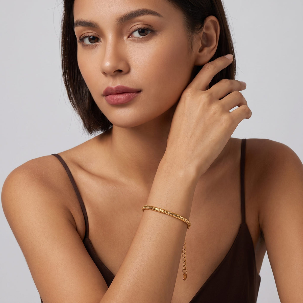 Woman with a dark bob wearing the Alessia snake chain gold bracelet near her chin