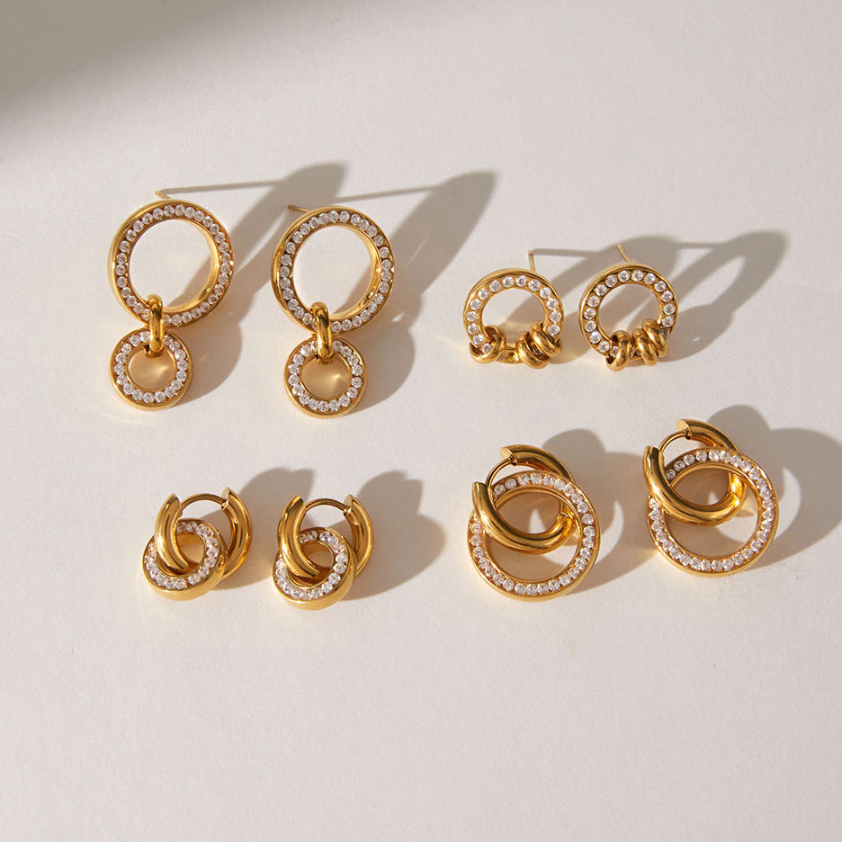 Apolline double circle earrings at the back left of a group of gold crystal earrings in sunlight
