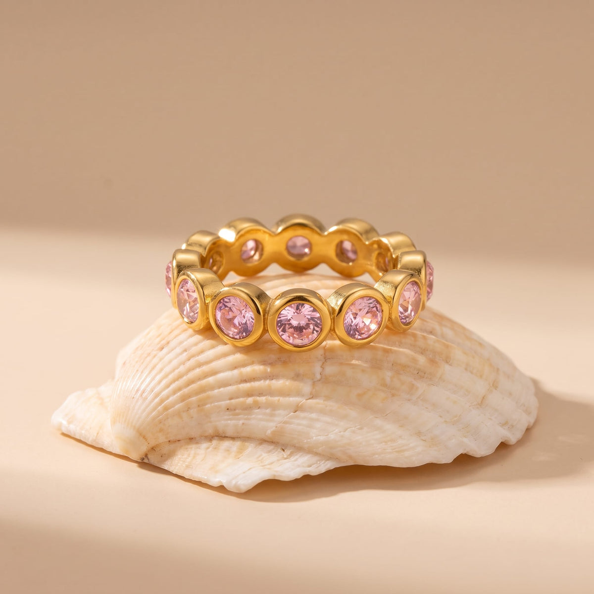 Ariana pink round gold ring on a seashell with a neutral background