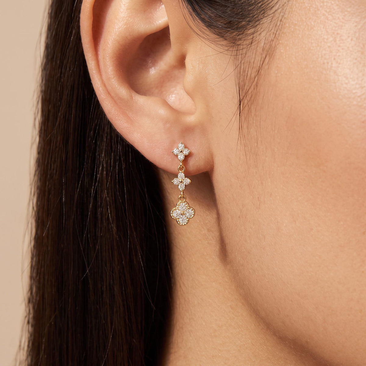 Woman wearing the Aurélie sparkle cluster earring, three clear crystal clovers in a gold drop