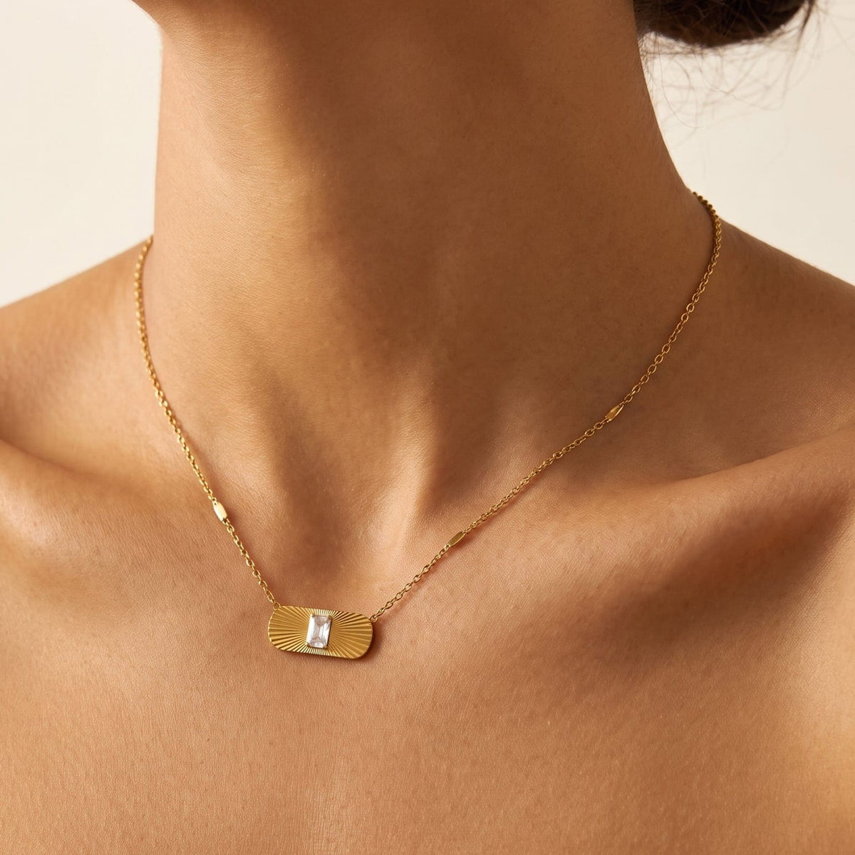 Woman wearing the Aurora sunburst crystal gold necklace at the collarbone