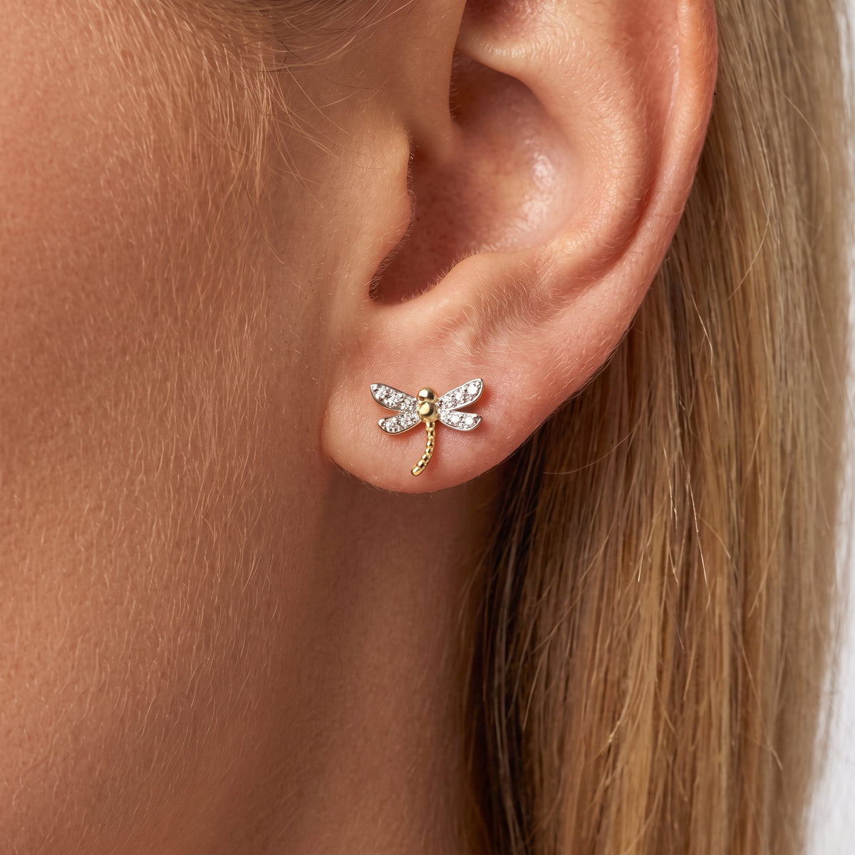 Woman wearing a Camille gold dragonfly stud with crystal wings on the ear lobe