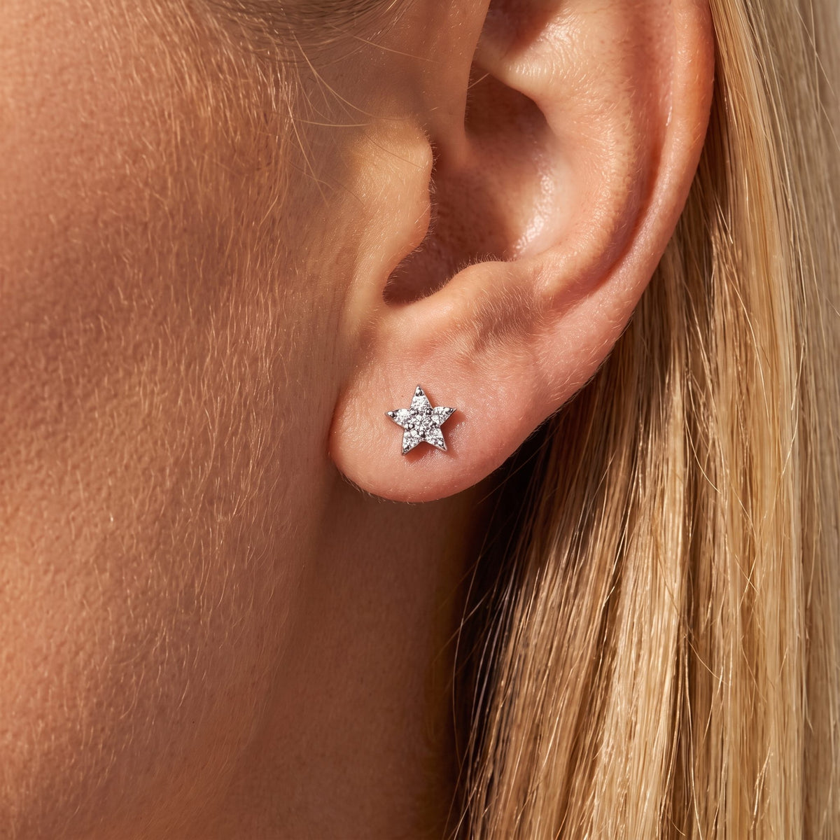 Woman wearing a Camille silver star stud set with pointed clear crystals on the earlobe