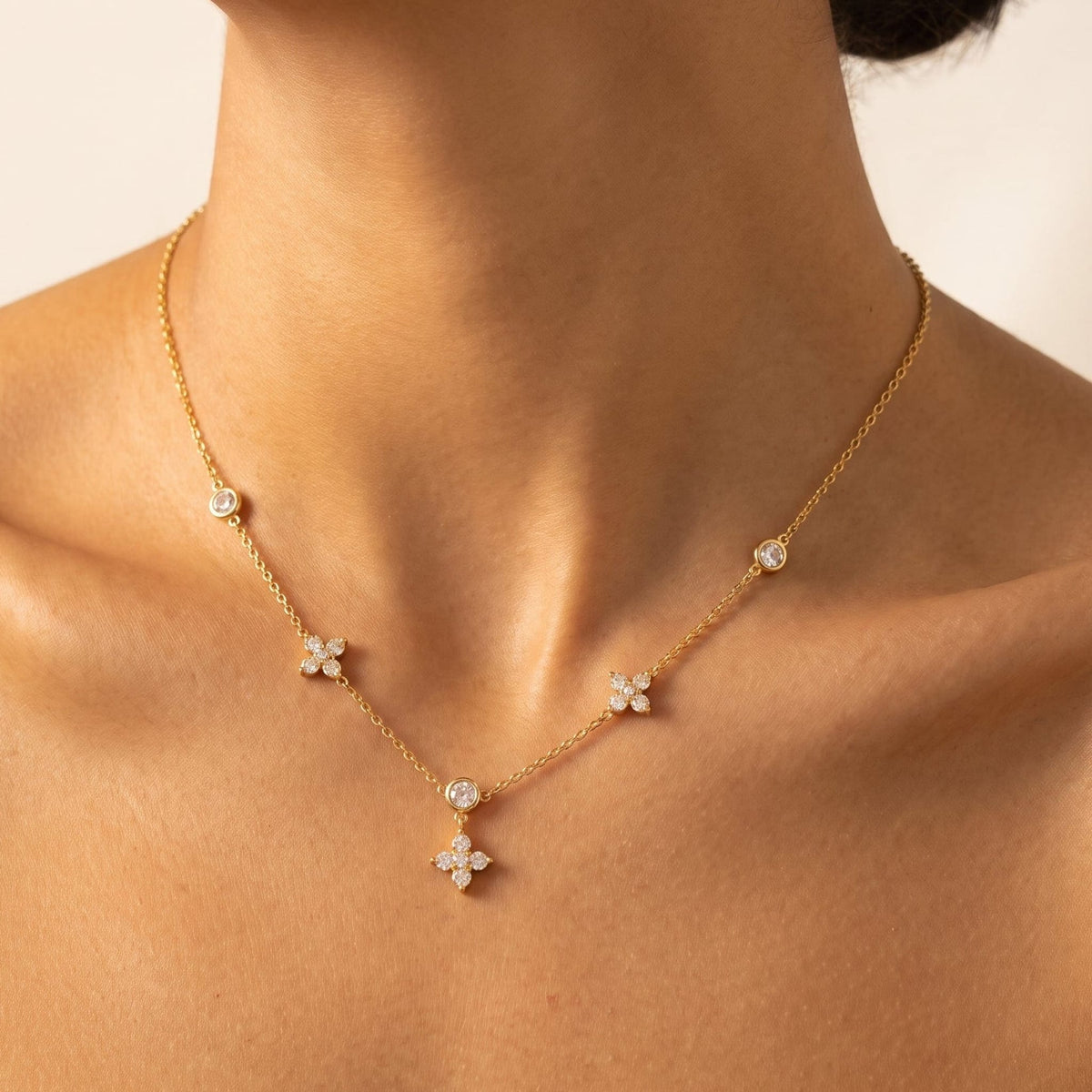 Woman wearing the Madeleine flower station gold necklace at the collarbone