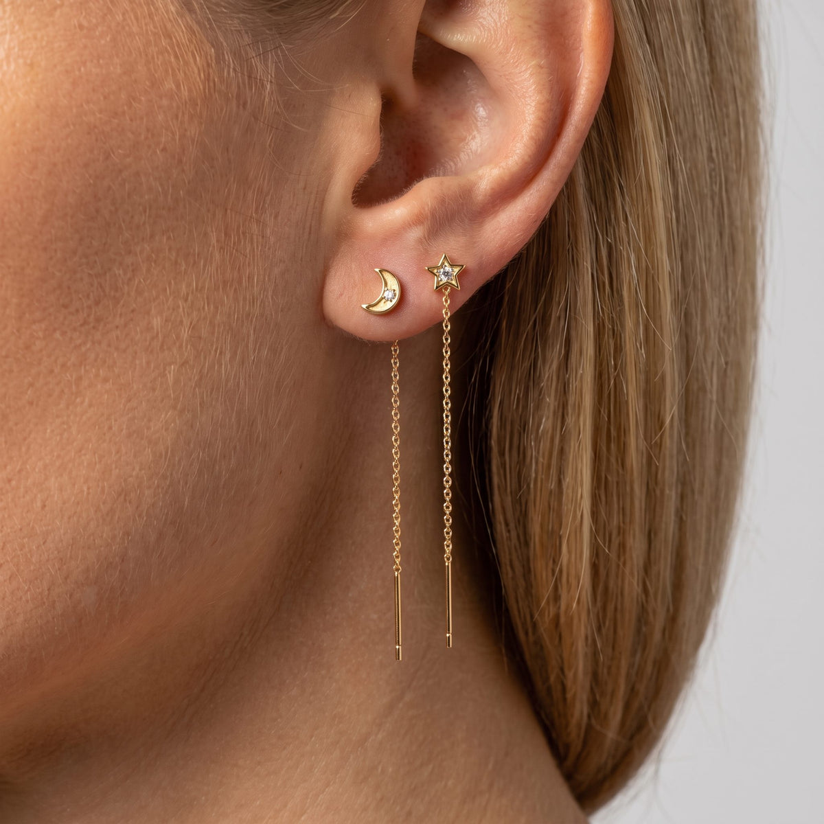 Woman wearing Celestia gold moon and star threader earrings in two piercings, fine chains falling below