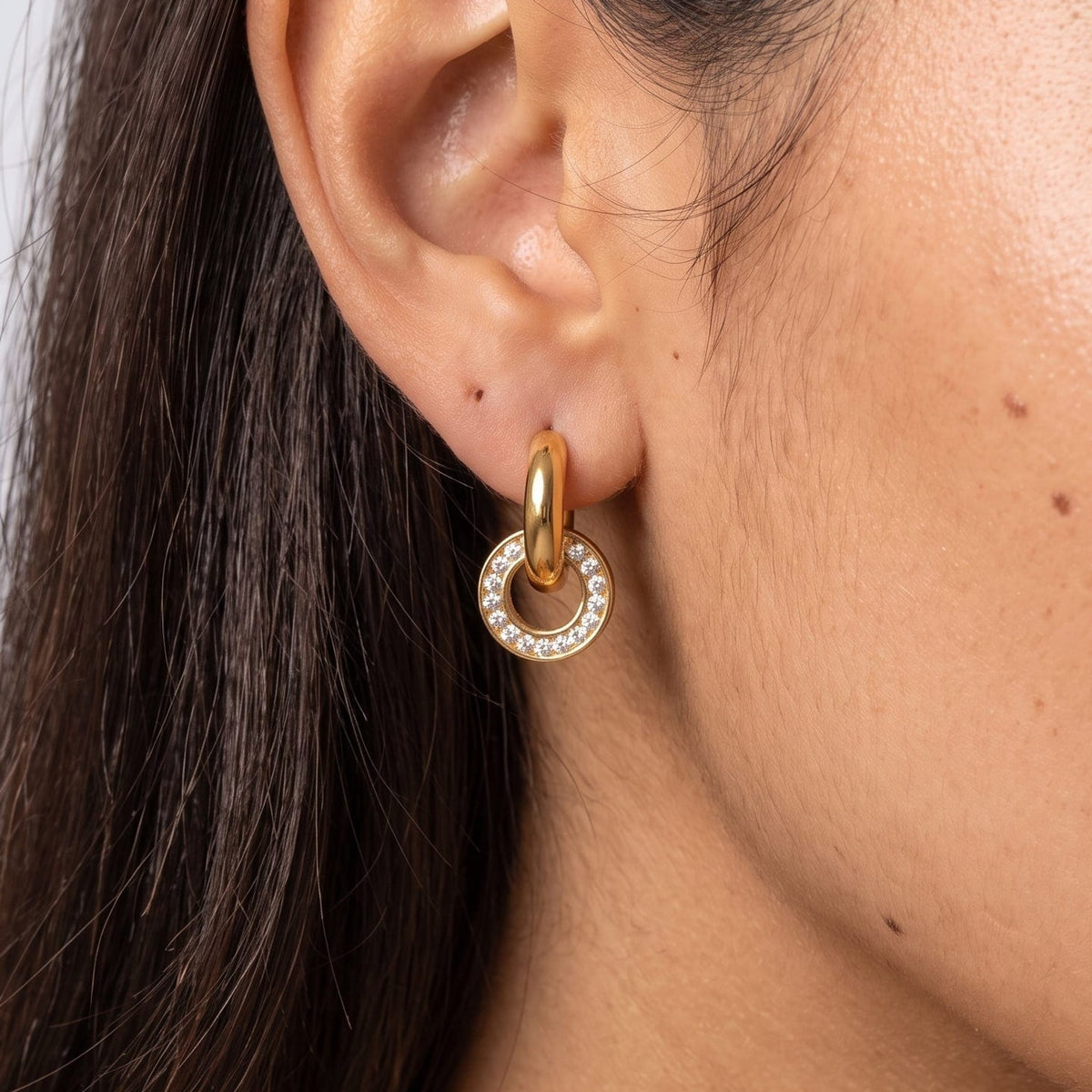 Woman wearing the Clémence circle huggie gold earrings on the ear