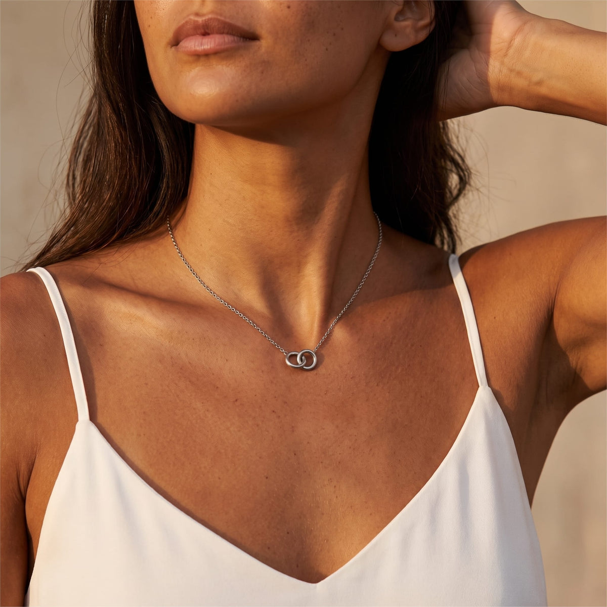Woman wearing the Colette interlocking rings silver necklace at the collarbone wearing a white camisole top