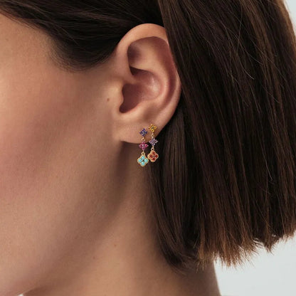 Close-up of a person wearing colorful earrings with a neutral background