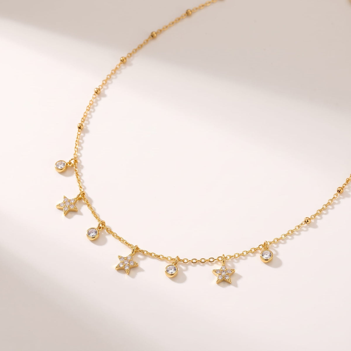 Delfina crystal star gold necklace on a white surface with soft shadows