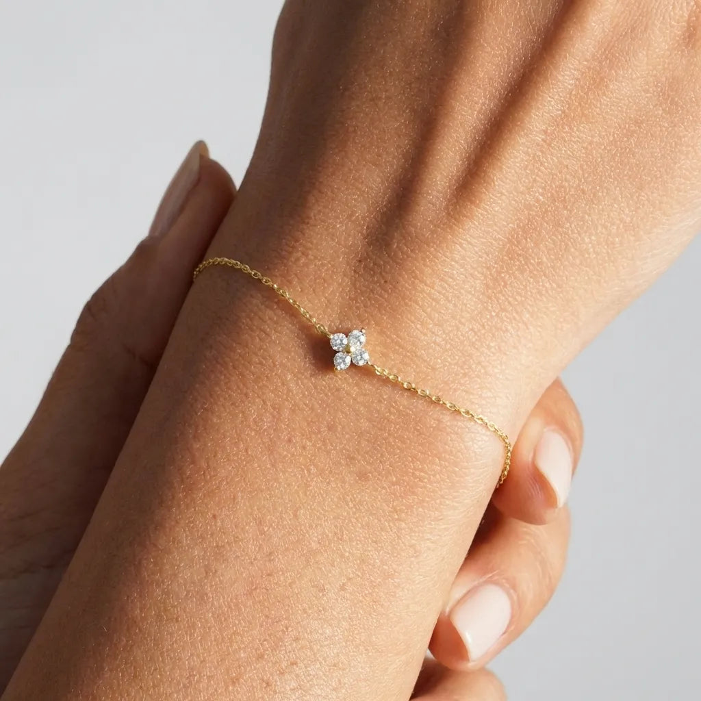 Woman wearing the Mia gold bracelet with a tiny crystal clover charm on the wrist