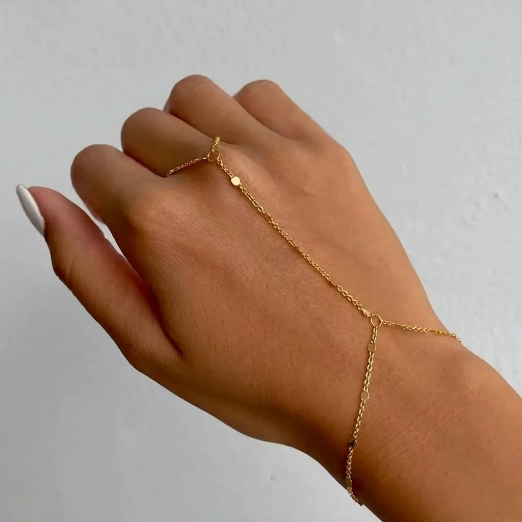 Woman wearing the Evelyne East gold hand chain with tiny disc stations running from wrist to finger