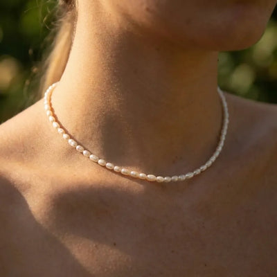 Woman wearing the Olivia necklace, a strand of small rice pearls close at the base of the neck