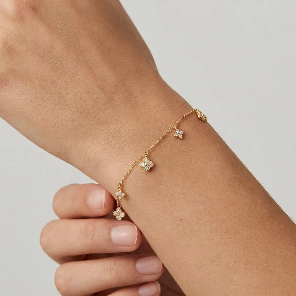 Woman wearing the Aurélie Glimmer Charm bracelet in gold, zircon clover charms dangling from the chain