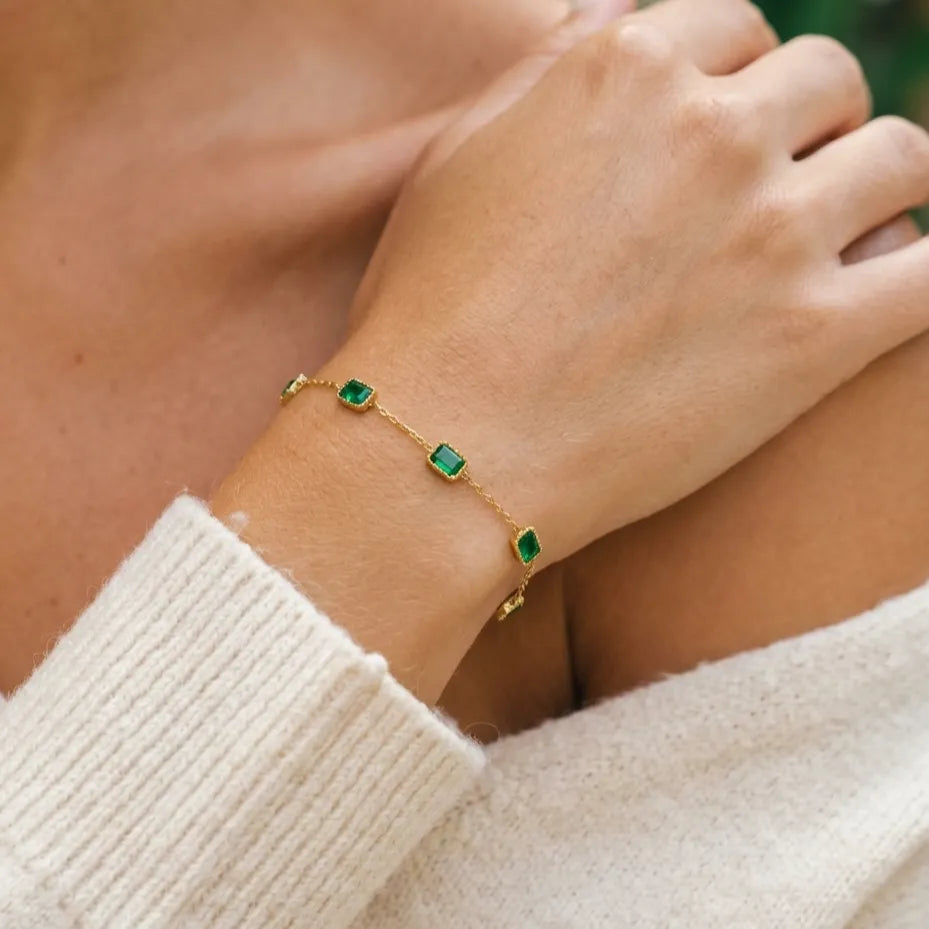 Francia green bracelet on the wrist, square green crystals in gold frames on a fine chain, knit sleeve below