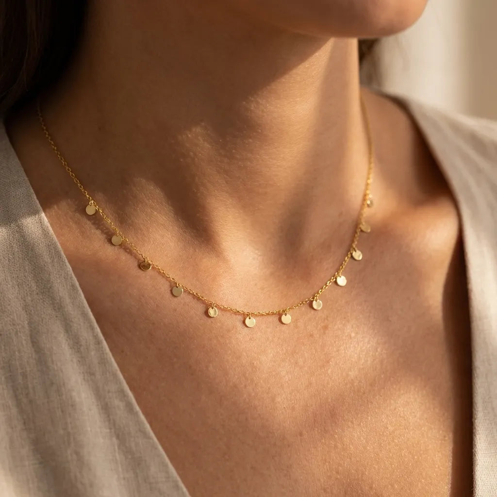 Woman wearing the Lucie dot charm necklace in gold with tiny disc charms hanging along the chain