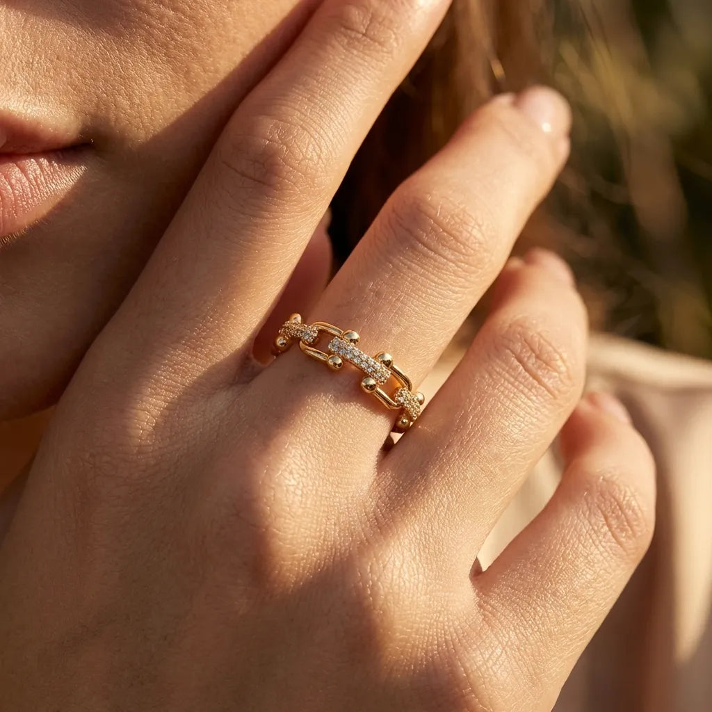 Woman wearing the Chloe gold chain-link ring with pavé crystal bars in warm sunlight