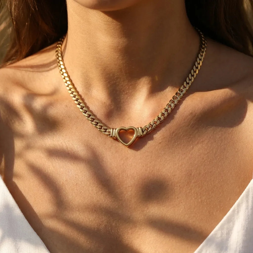 Woman wearing the Vali gold curb chain choker with an open heart centerpiece at the throat