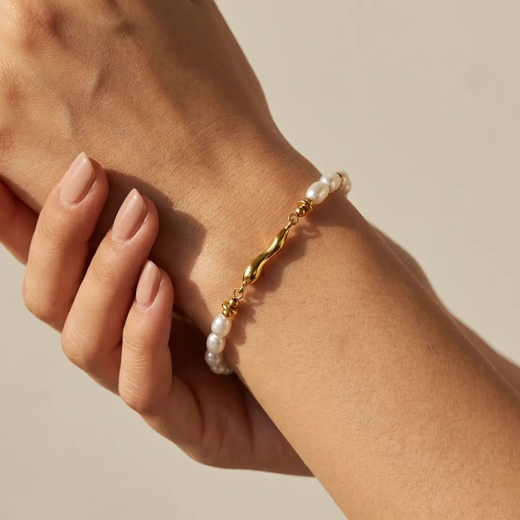 Quintessa Pearl bracelet on the wrist, freshwater pearls around a curved gold bar