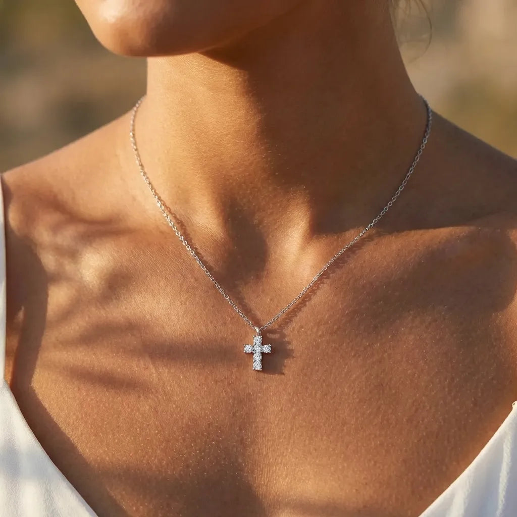 Woman wearing the Chloé silver cross pendant set with crystals, in warm sunlight