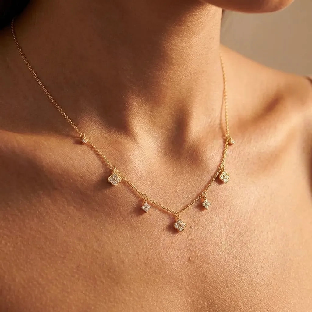 Woman wearing the Aurélie glimmer charm necklace in gold with small crystal clover charms dangling