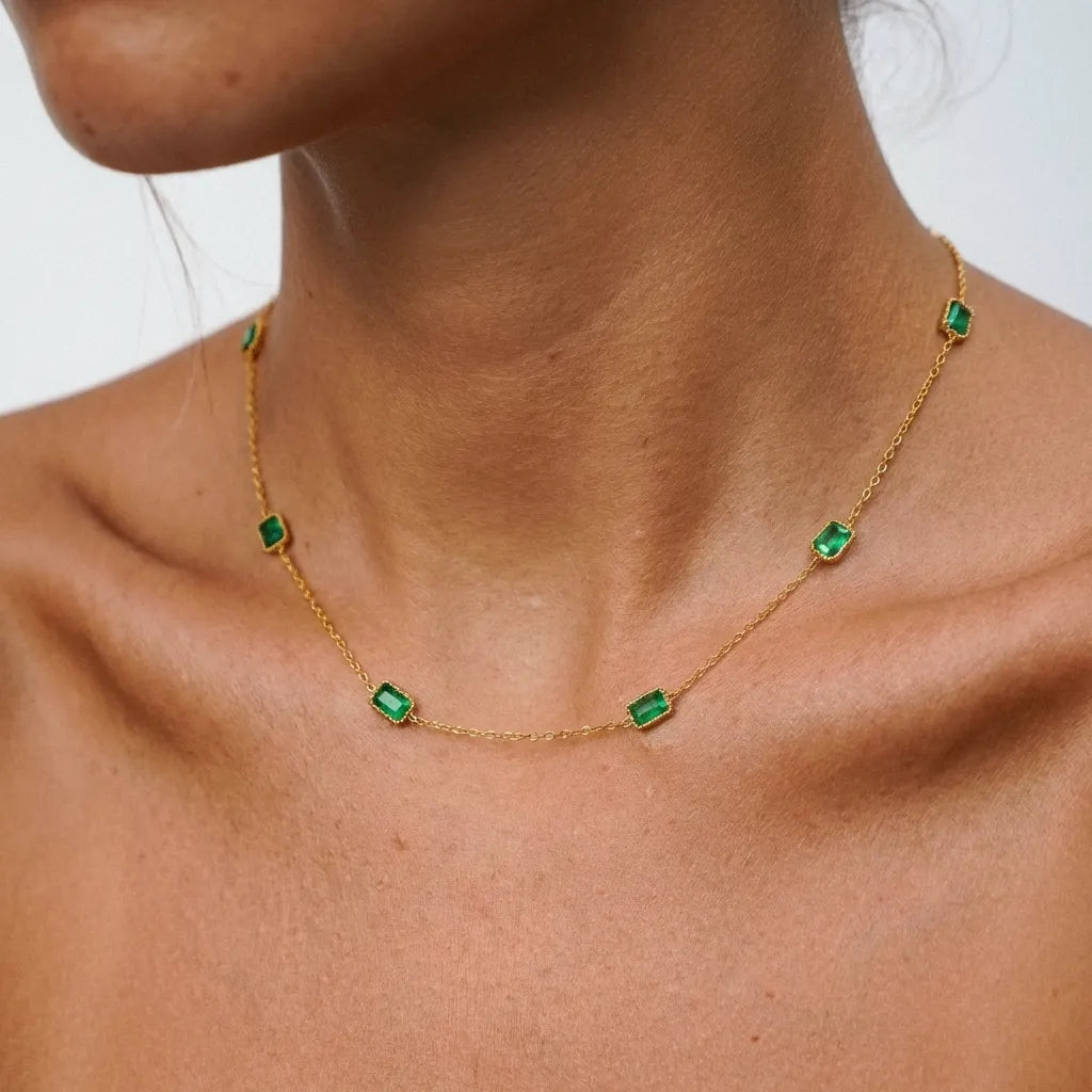 Woman wearing the Francia gold necklace with small rectangular green crystal stations around the neck