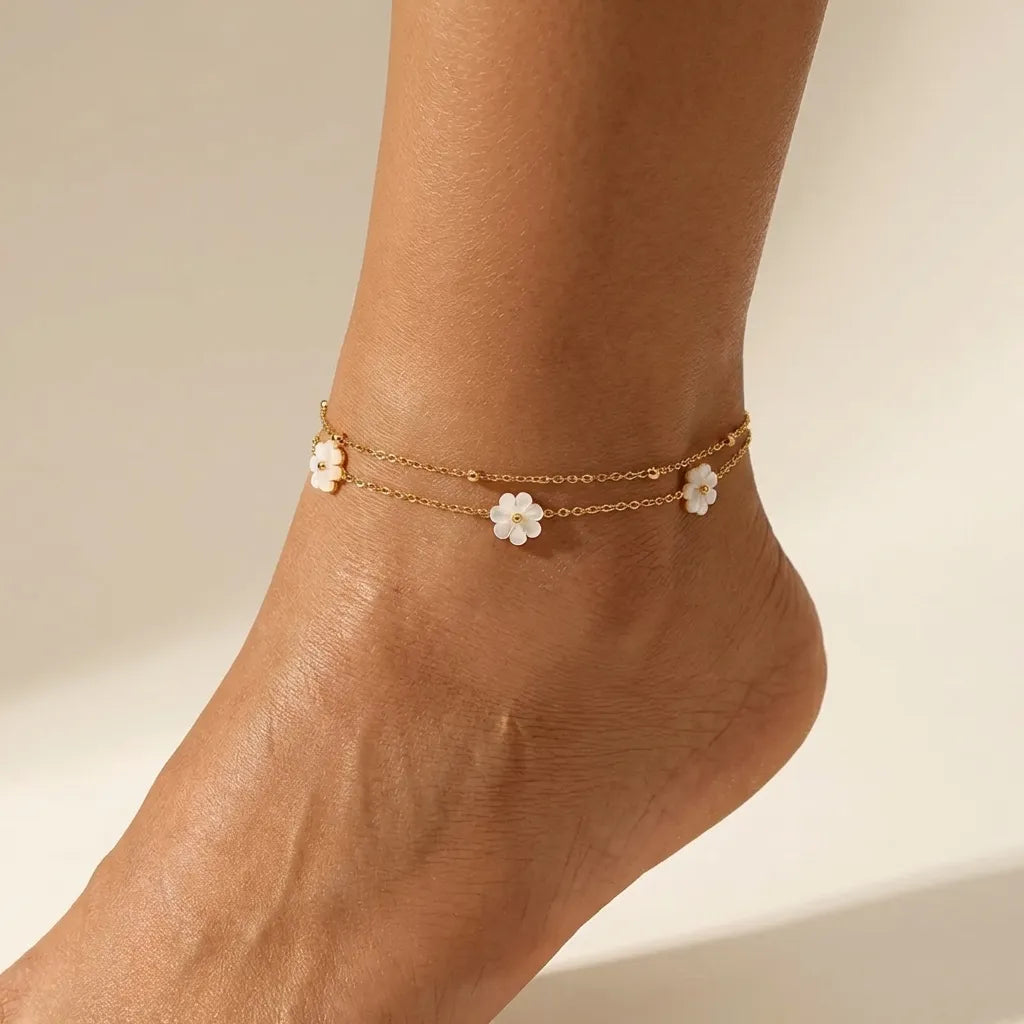 Camille white flower anklet worn on the ankle, three white blossoms spaced along a double gold chain