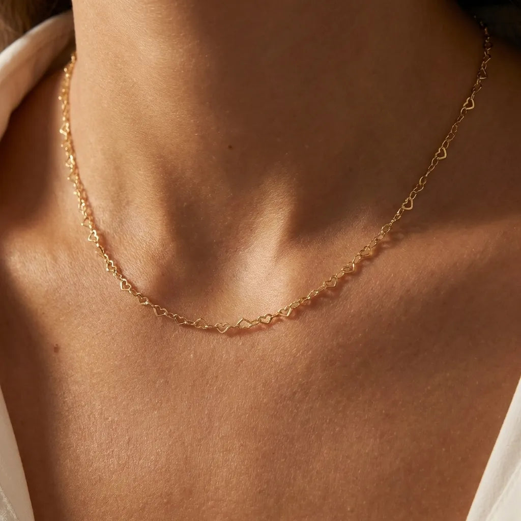 Woman wearing the Élodie gold chain made of tiny open heart links at the collarbone