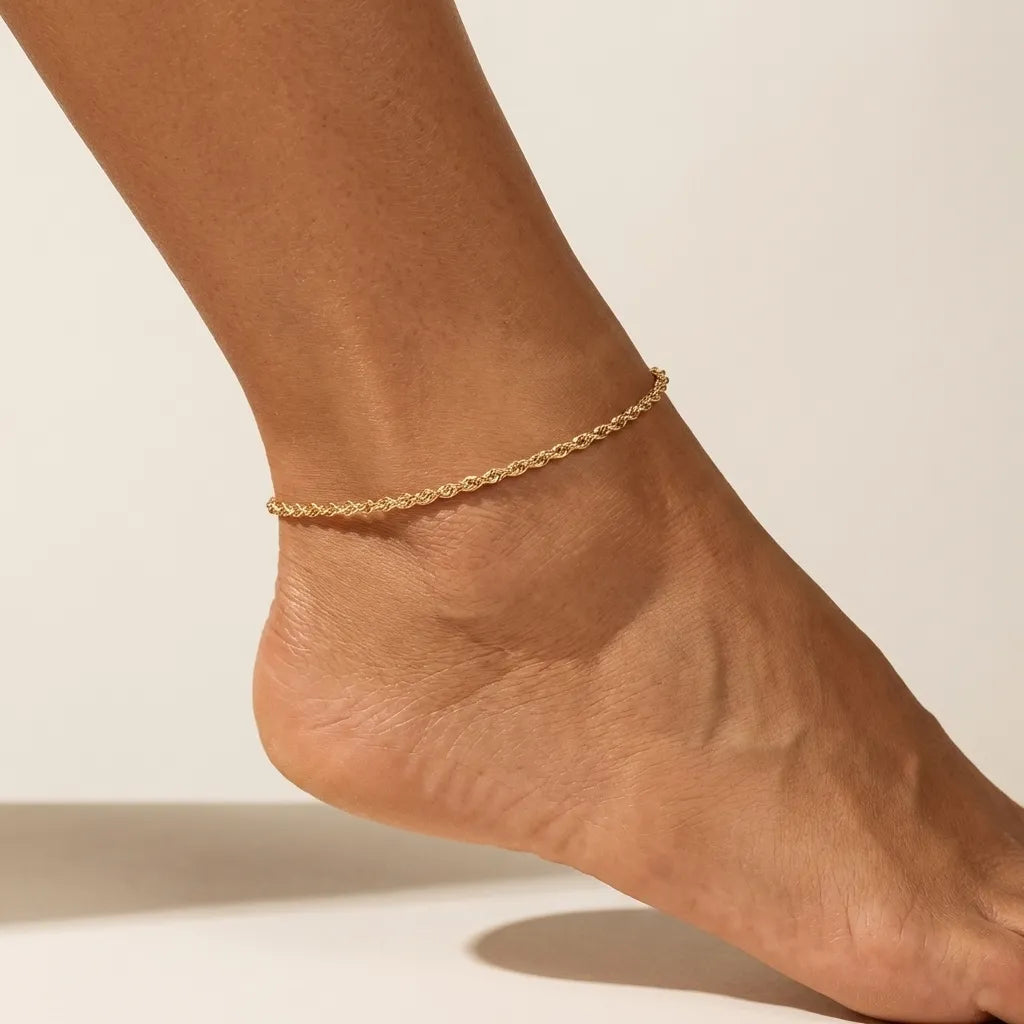 Woman wearing the Calla rope anklet in gold, a twisted rope chain resting above the heel