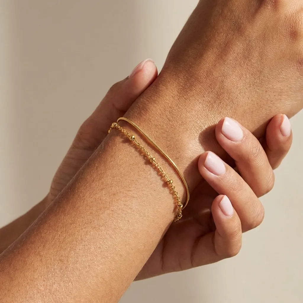 Evelyne layered gold bracelet with a snake chain and a satellite bead chain stacked on the wrist
