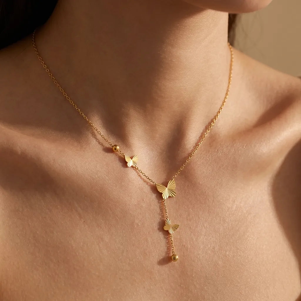 Woman wearing the Bella gold necklace, three ribbed butterflies falling down a Y-shaped chain