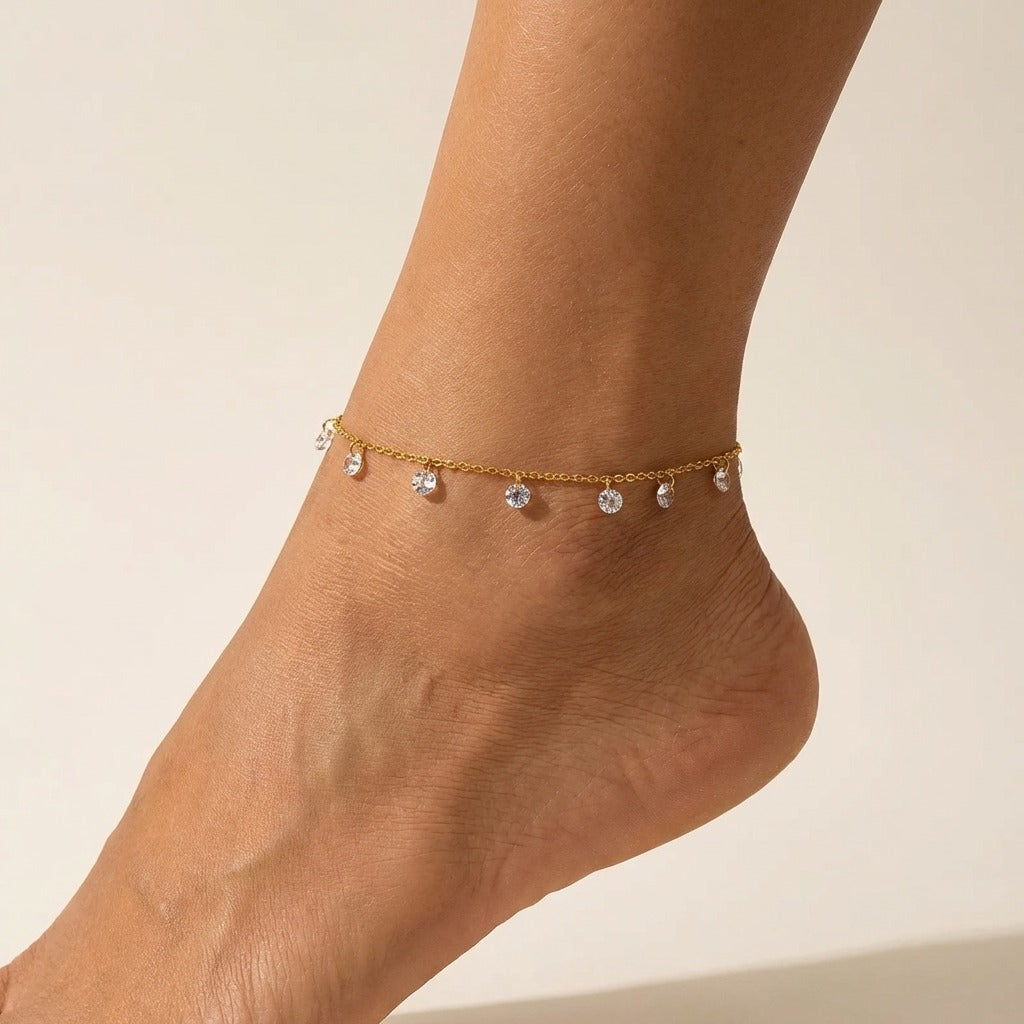 Amélie sparkle charms anklet in gold on the ankle, clear crystal drops hanging along a fine chain