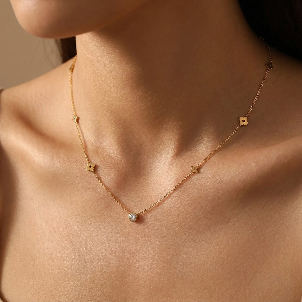 Woman wearing the Élina gold clover station necklace with a single crystal at the center