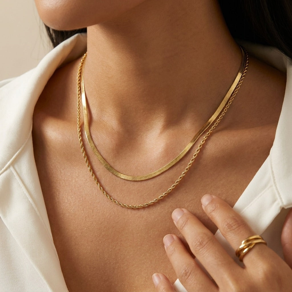 Woman in a white blazer wearing the Vida double gold necklace, a herringbone and a rope chain layered