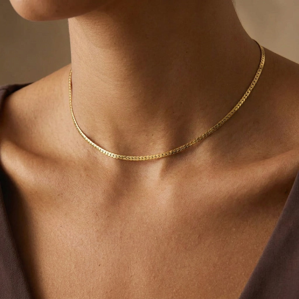 Woman wearing the Hanna gold flat chain necklace close at the base of the throat
