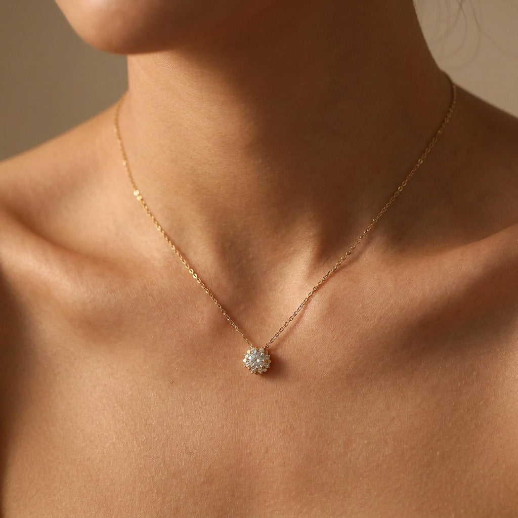 Woman wearing the Elisa sun gold necklace, a round crystal sunburst pendant at the collarbone