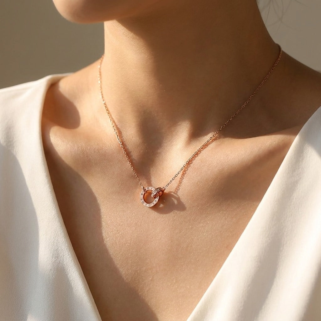 Woman in a white wrap top wearing the Ramona rose gold necklace with interlocking crystal circles