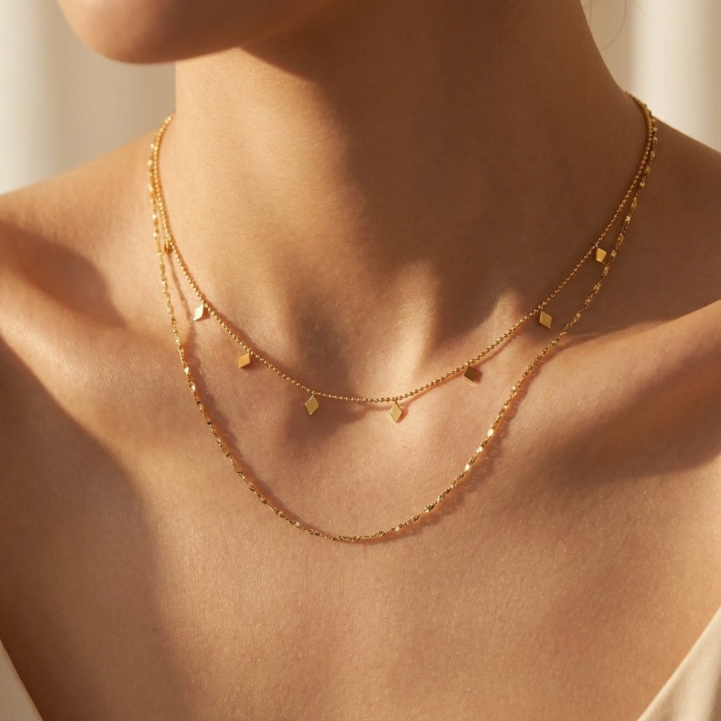 Woman wearing the Penelopa layered gold necklace, tiny geometric charms above a twisted chain