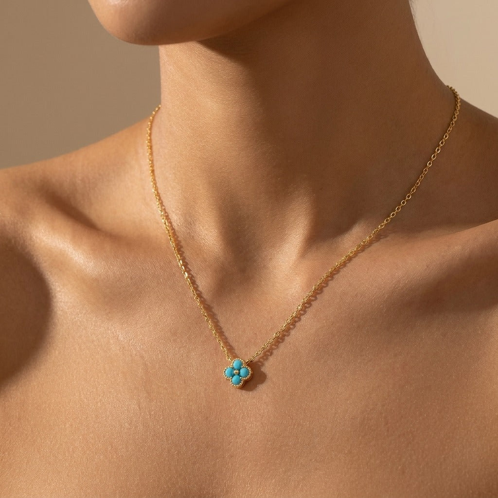 Woman wearing the Aurélie crystal pendant necklace in gold with a turquoise-blue clover pendant