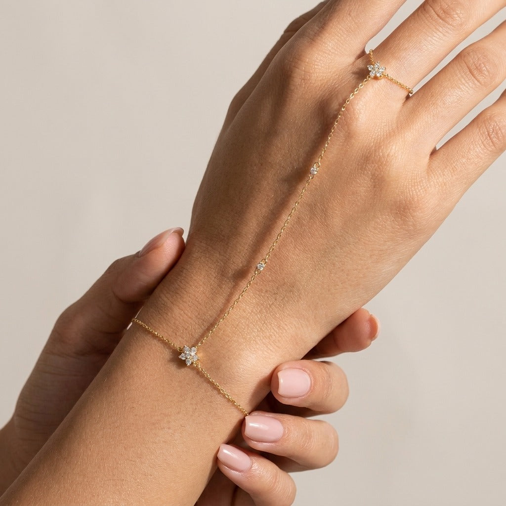Woman wearing the Amélie gold hand chain with crystal flowers at the wrist and on the finger ring