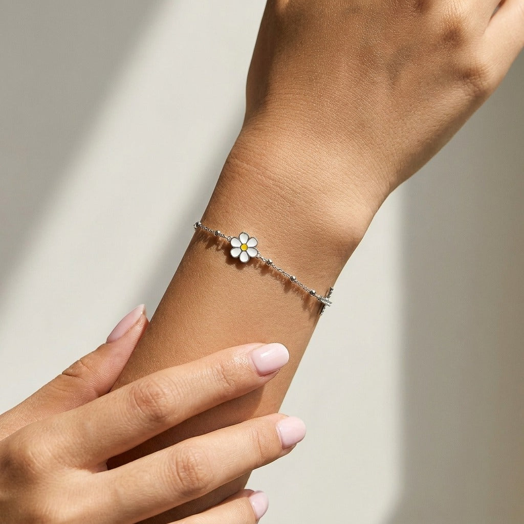 Woman wearing the Elise Marguerite silver bracelet with a white daisy charm on a beaded chain