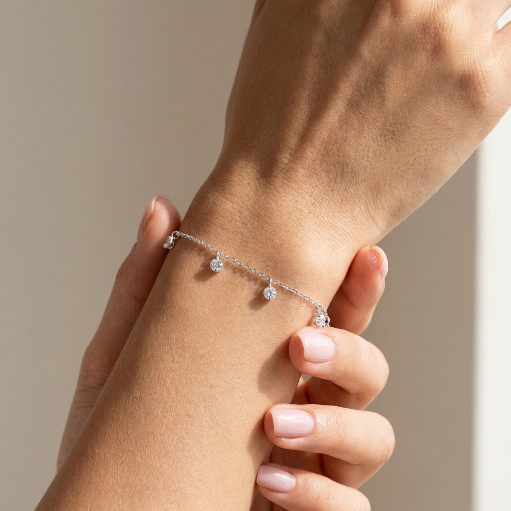 Woman wearing the Elise Sparkling Dew silver bracelet with small crystal drops hanging from the chain