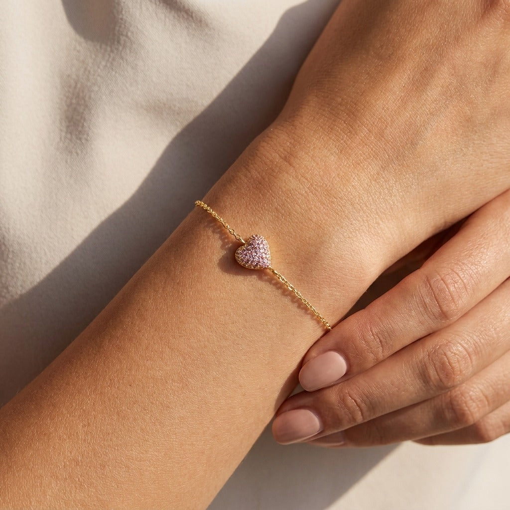 Woman wearing the Amélie Coeur gold bracelet with a pink crystal pavé heart on the wrist