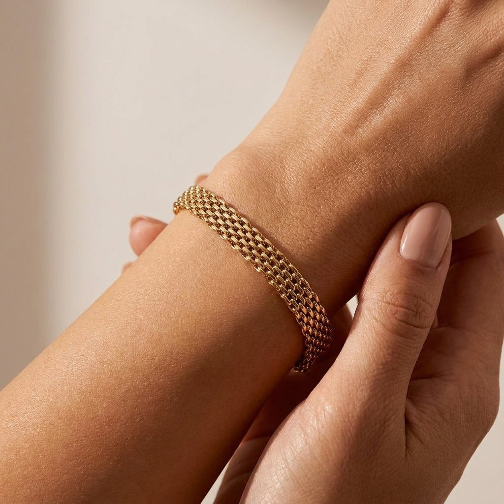 Woman wearing the Imara gold chain bracelet, a wide woven mesh band, on the wrist