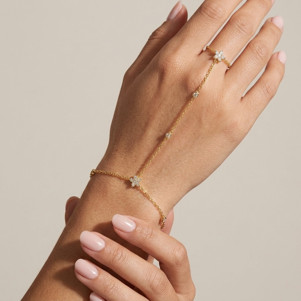 Woman wearing the Vivienne gold hand chain linking a crystal flower at the wrist to a flower ring