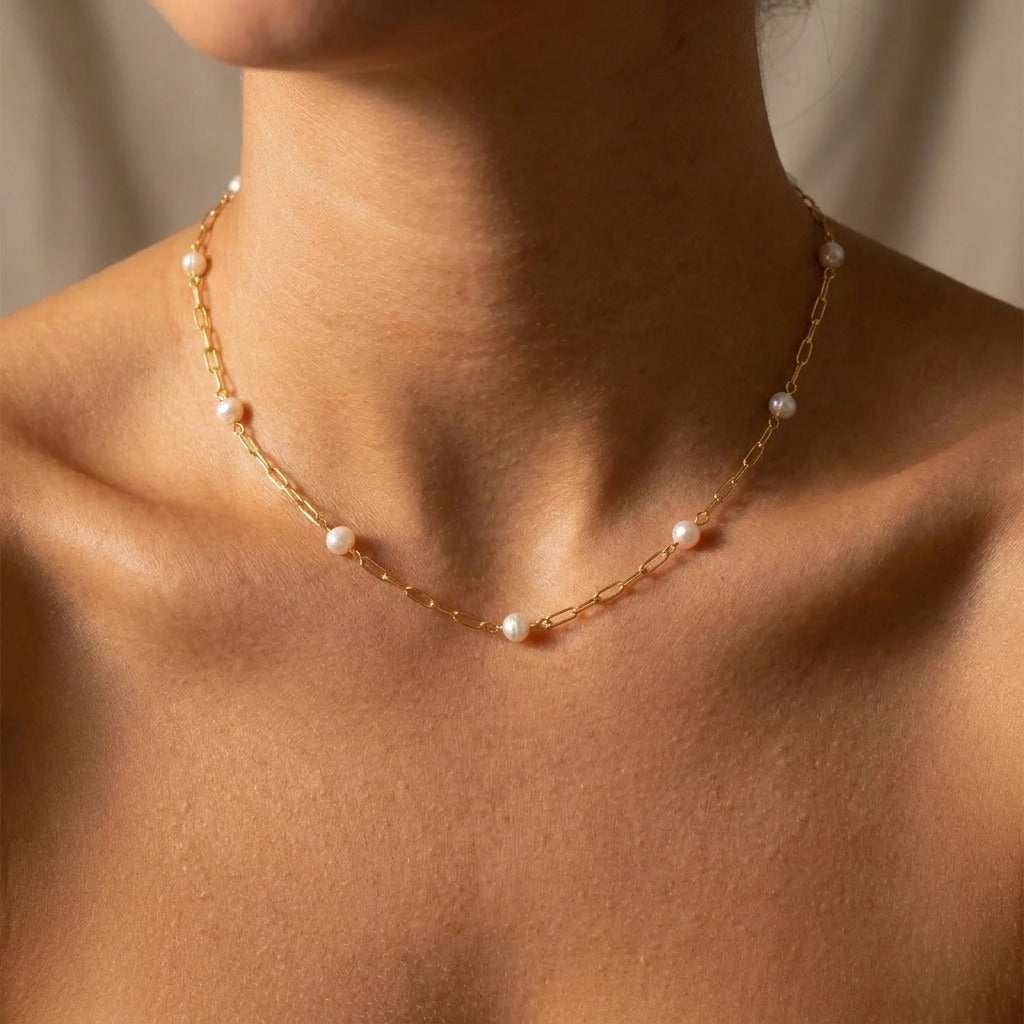 Woman wearing the Léa dainty pearls necklace, pearls spaced along a gold paperclip chain