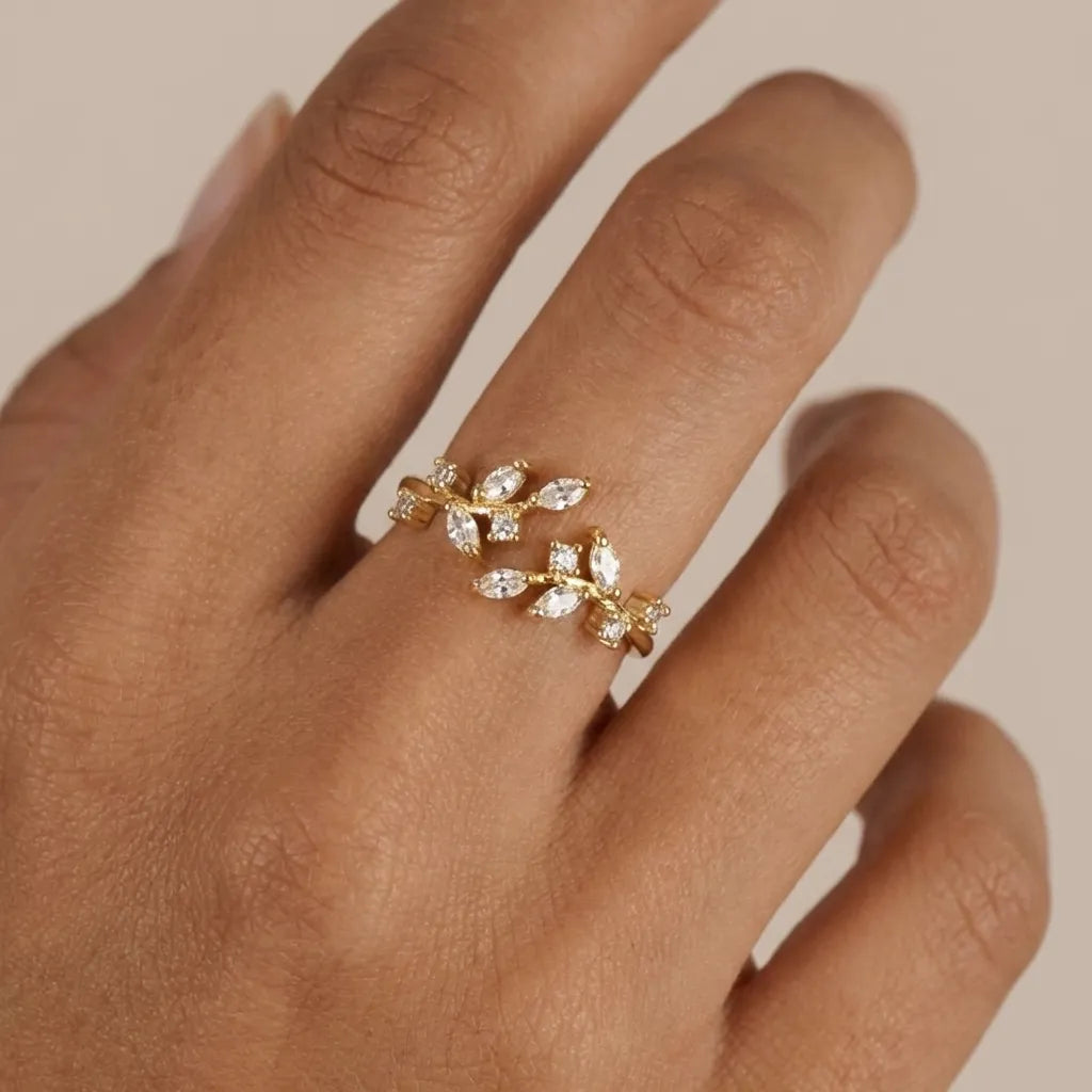 Hand wearing the Flora open gold ring with crystal-set leaf branches meeting on top