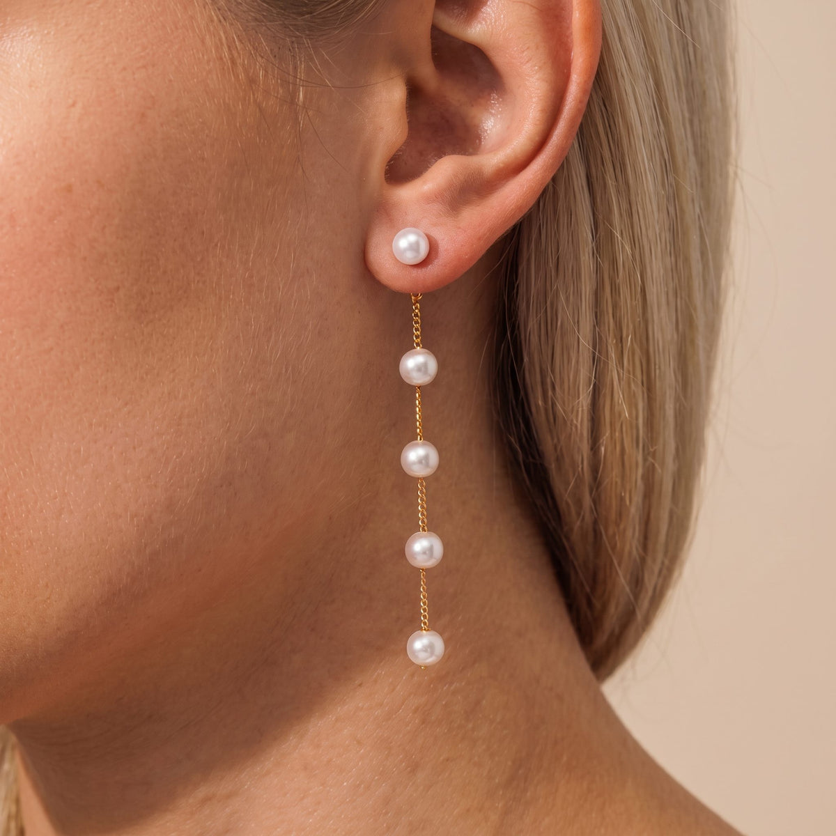 Woman wearing the Élise drop pearl earring with pearls spaced along a fine gold chain